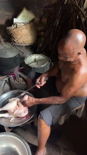 Man prepares chicken meal in rural Nigerian kitchen