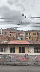 Cable cars operate above La Paz cityscape under cloudy skies