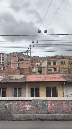 Cable cars operate above La Paz cityscape under cloudy skies