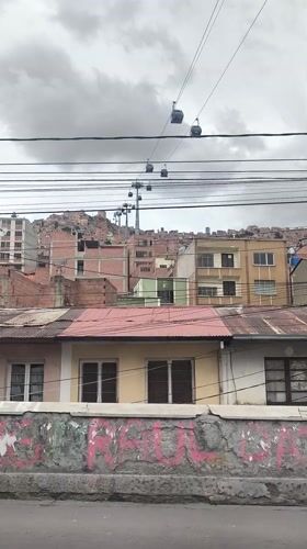Cable cars operate above La Paz cityscape under cloudy skies