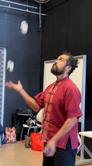 Man juggles balls and clubs in indoor space