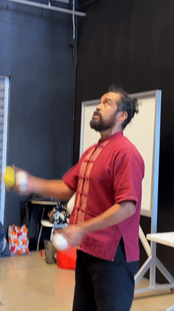 Man juggles balls and clubs in indoor space
