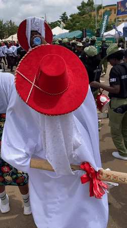 Traditional procession with robed figures and adorned horses in Alagba