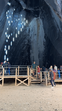 Inside a Romanian salt mine cavern, lit walkway below ground.