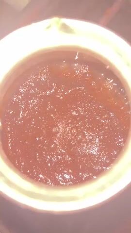 The video shows a close-up view of dark, frothy liquid bubbling in a copper pot. The liquid appears to be coffee being brewed. The pot is sitting on what looks like a stovetop. The video is shot from above, looking down into the pot.