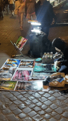 Masked street artist creates art on Rome cobblestones