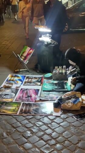 Masked street artist creates art on Rome cobblestones