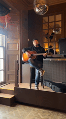 Acoustic guitarist performs on wooden platform in Dundee venue