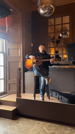 Acoustic guitarist performs on wooden platform in Dundee venue