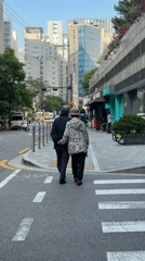Elderly couple crosses Seoul street hand-in-hand