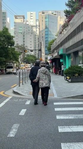 Elderly couple crosses Seoul street hand-in-hand