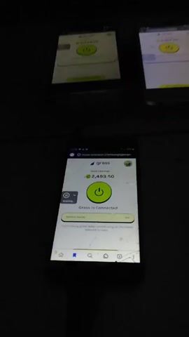The video shows a cell phone lying on a surface. The screen is cracked and displays the "Grass" app interface, indicating a connection with 2,493.50 currency and a 75% network quality. The text below states "You're doing great! Keep contributing on the Grass Network to earn." Additionally, the screen shows navigation icons and a status indicator displaying "Waiting..."