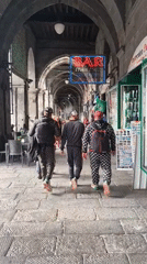 Three men in tracksuits walk through Genoa archway