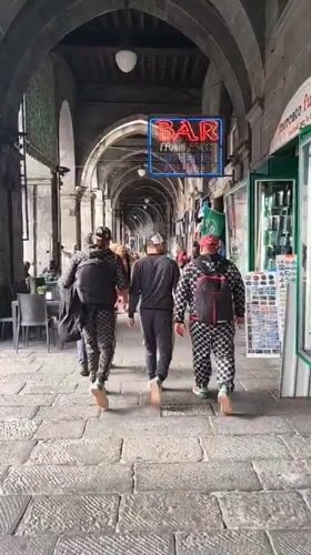 Three men in tracksuits walk through Genoa archway