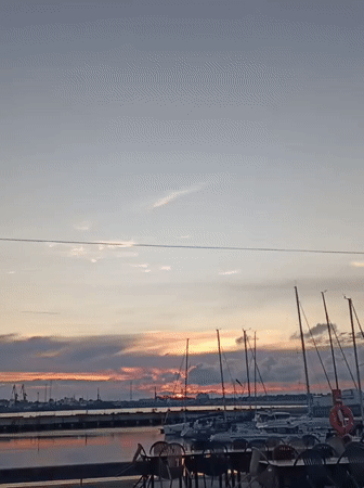 Tallinn harbor at sunset, sailboats docked under a colorful sky