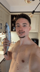 Man holds raw fish in Sofia kitchen selfie