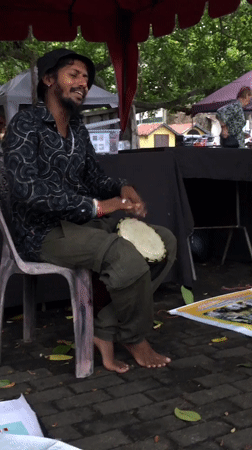 Street musician performs drums under stormy skies in Galle