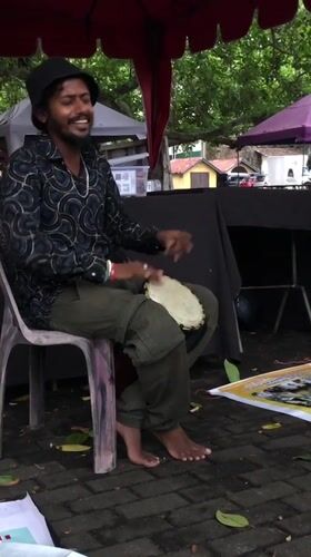 Street musician performs drums under stormy skies in Galle