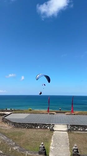 Paragliders soar over Bali's southern coast on a clear day
