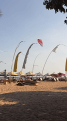 Kites, kitesurfers, and ceremony flags on a Bali beach