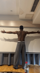 Man poses with outstretched arms indoors in Liangjiang