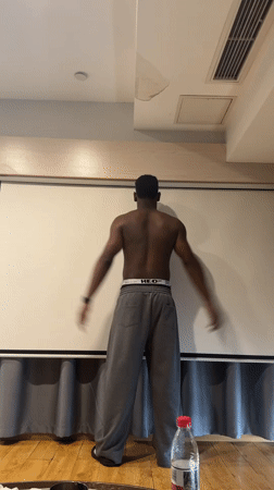 Man poses with outstretched arms indoors in Liangjiang