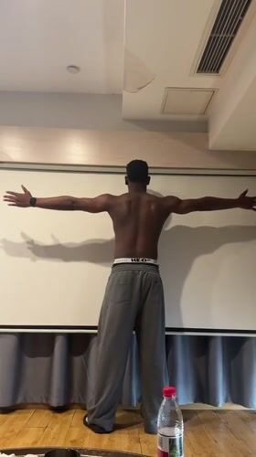 Man poses with outstretched arms indoors in Liangjiang