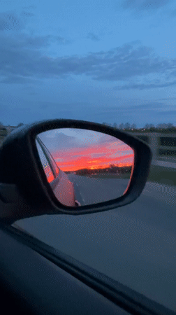 Motorist captures vivid sunrise reflected in rainy car mirror