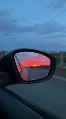 Motorist captures vivid sunrise reflected in rainy car mirror