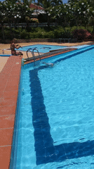 Woman sits poolside at Phú Thủy resort on sunny day