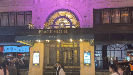 Crowds gather at illuminated Peace Hotel, Shanghai shopping district