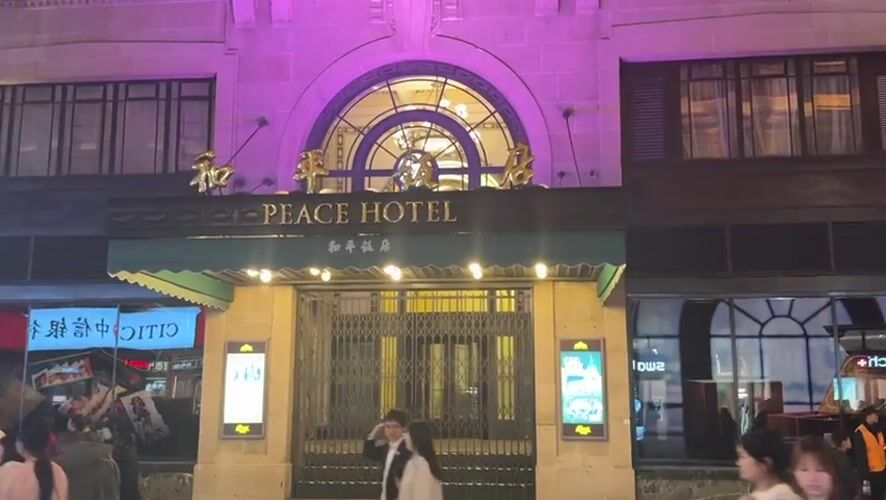 Crowds gather at illuminated Peace Hotel, Shanghai shopping district