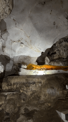 Woman meditates at cave temple with reclining Buddha statue