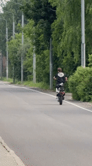 Dirt bike rider performs wheelie on Russian street