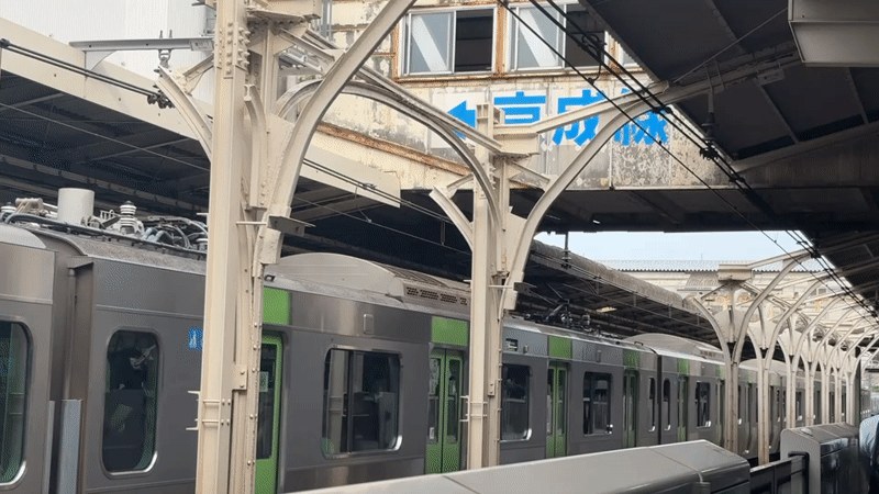 Silver and green train paused at an Arakawa station platform.