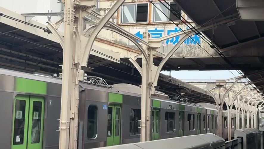 Silver and green train paused at an Arakawa station platform.