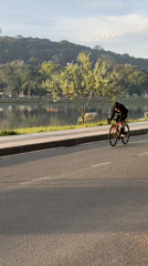 Cyclist rides red bicycle along lakeside road in Da Lat