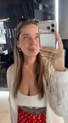 Woman in polka dots takes selfies in marble interior