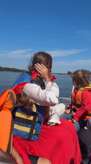Group outing on a boat, life vests on, sunny skies