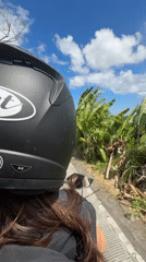 Woman rides motorcycle through agricultural fields in North Kuta