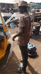 Man spray paints yellow three-wheeled vehicle outdoors