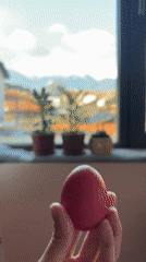 Person holds pink egg near plant-filled windowsill in Bansko