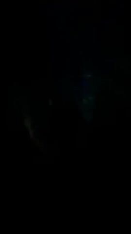 A dimly lit nightclub scene captures a crowded dance floor. People are silhouetted against flashing blue and green lights that emanate from above. The focus shifts between close-up shots of individuals and wider views of the packed venue. Some individuals are raising their hands in the air, indicating dancing and enjoyment. The ceiling features a grid of blue lights with small white dots, possibly simulating stars. The overall atmosphere is energetic and typical of a nightclub environment.