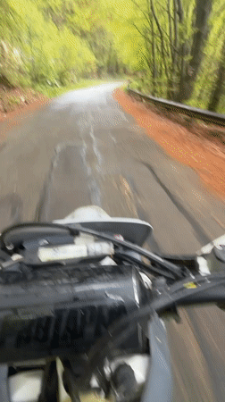 Motorcyclist rides wet forest road near Shipka, Bulgaria
