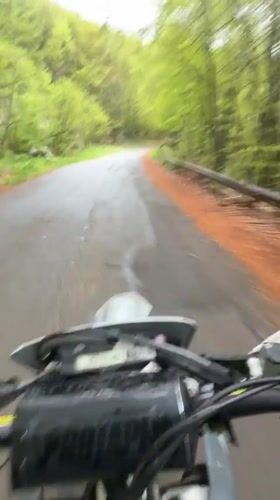 Motorcyclist rides wet forest road near Shipka, Bulgaria