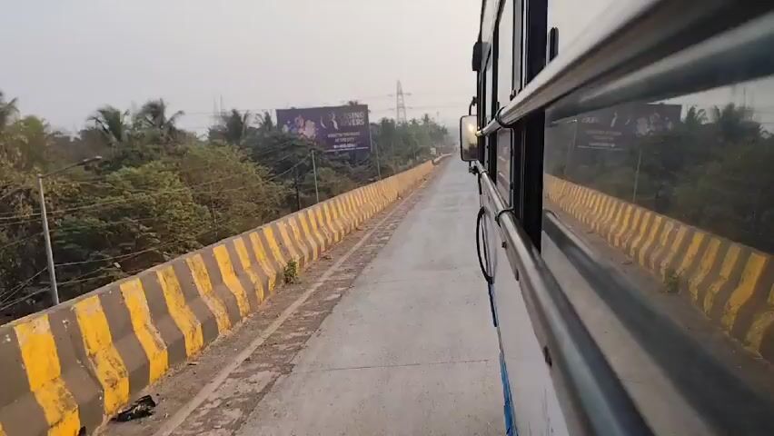 A bus drives down a concrete bridge lined with yellow and black striped barriers. A large billboard advertising "Casino Rivers" is visible on the left side of the road. The sky is overcast. Trees are visible in the distance.