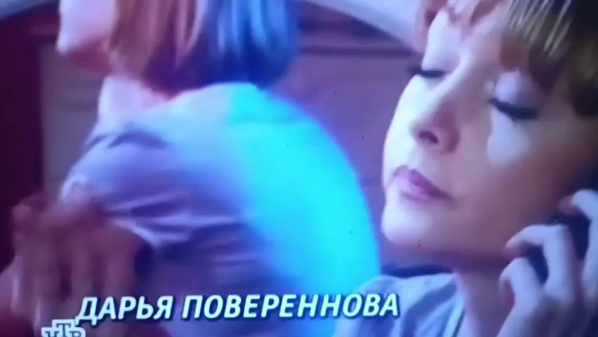 The video begins with a close-up of a woman with reddish-brown hair, looking stressed as she speaks on a mobile phone. Text appears on the screen that reads "ДАРЬЯ ПОВЕРЕННОВА". The scene cuts to a man in a dark suit and tie talking on a mobile phone outside a brick building. The man is positioned to the right of the frame, with a dark shadow cast on the brick wall behind him. The video then cuts back to the woman, who appears to be in a car, looking at something in her hands. Text on the screen reads "АНДРЕЙ БАЖИН". The woman is still on the phone and appears distressed. The final shot shows the woman again, looking concerned while on the phone.