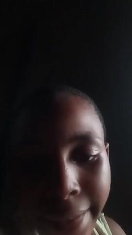 A close-up shot shows the face of a young person against a dark background. The person's head is tilted slightly down, and their eyes are partially closed. Their lips are slightly parted, as if they are about to speak or have just finished speaking. The lighting is dim, casting shadows on the face and obscuring details. The person appears to be wearing a light-colored garment. The timestamp in the upper left corner indicates the video begins at 00:00.