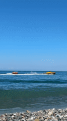 Pebble beach day with tubing boats on the water