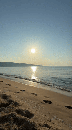 Dawn breaks over Nesebar beach as sunrise illuminates calm waters